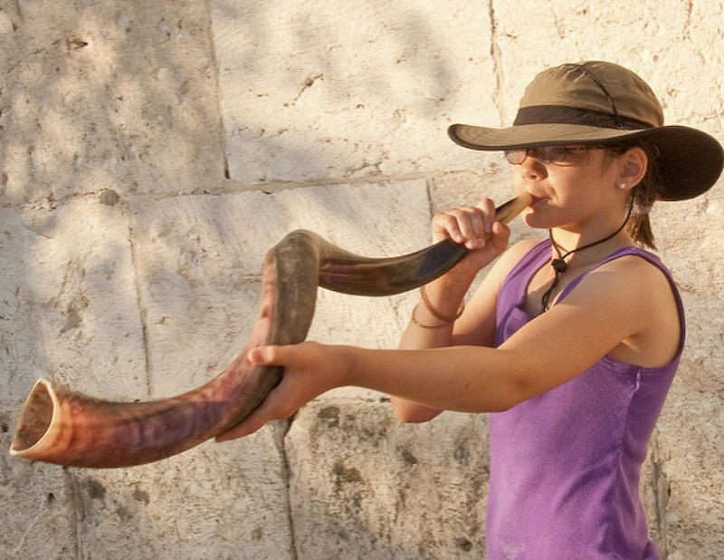 Girl blowing shofar at the Kotel.