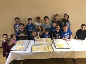Cantor Shana teaching kids how to make challah.